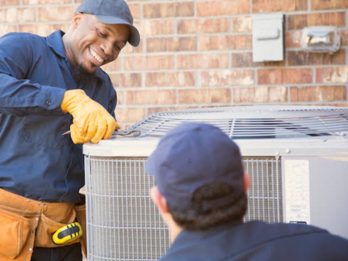 Two HVAC technicians working on a residential unit together